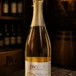 Sektflasche Jungwinzersekt Jahrgang 2022 auf dunklem Schiefer in einem Weinkeller.