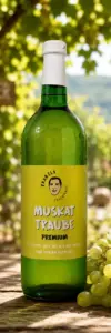 Produktfoto-Muskat-Traube-Premium-Heuriger Eine grüne Glasflasche mit Traubensaft von „Franzls Fruchtsäfte“ steht im Fokus auf einem rustikalen Holztisch in einem sonnendurchfluteten Heurigen-Weingarten. Im weich gezeichneten Hintergrund schimmern grüne Weinreben im warmen Nachmittagslicht. Neben der Flasche liegt eine frische Rebe grüner Muskat-Trauben.